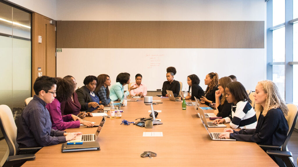 Nonprofit board meeting in a conference room. Board members are sitting around a wooden conference table.