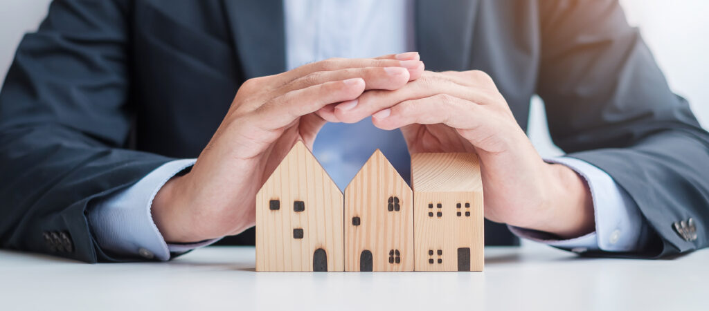 Businessman hand cover wooden Home model real estate insurance and property concepts Businessman hand cover wooden Home model real estate insurance and property concepts