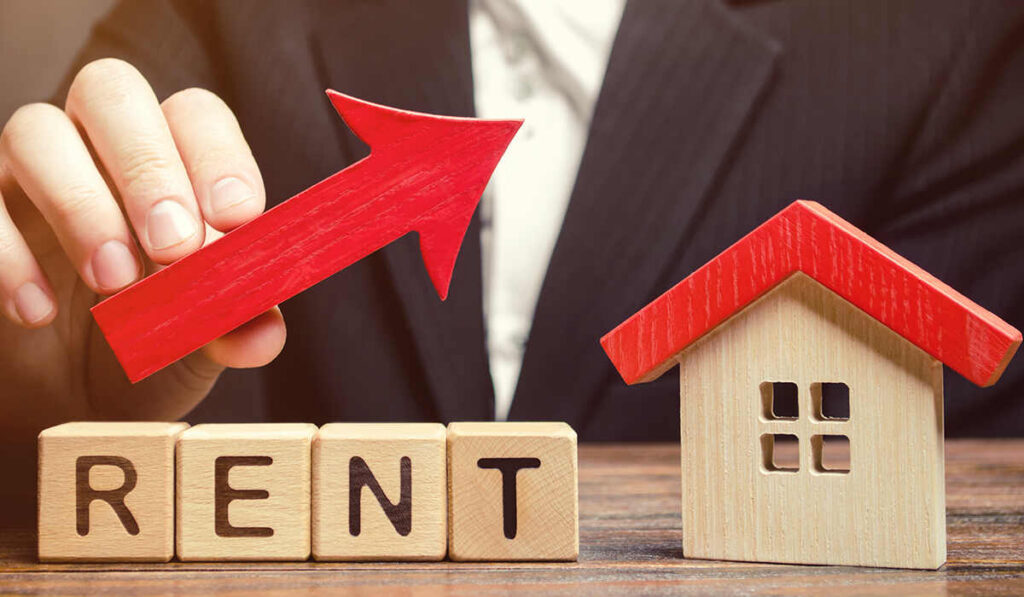 Conceptual real estate photo showing a rental price increase with an upward red arrow and a small wooden house.