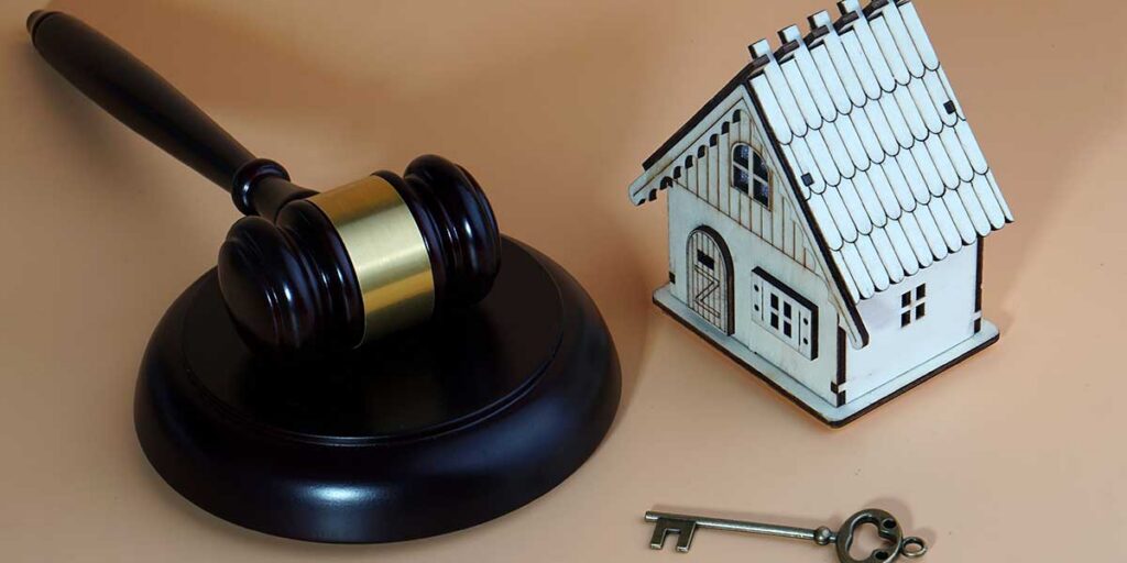 A wooden gavel rested beside a small model house and key, representing legal protections for South Carolina property owners.